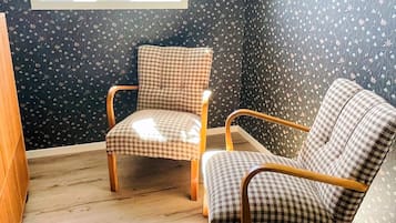 Una habitación con dos sillas a cuadros, una ventana con vistas y papel tapiz estampado.