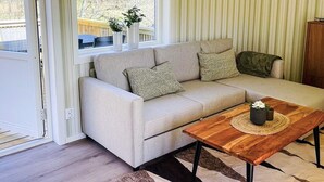 A living room with a sofa, a coffee table, a window, and a picture on the wall. - 4 Star Holiday Home in Bodafors (Bodafors)