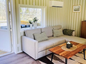 A living room with a sofa, a coffee table, a window, and a picture on the wall. - 4 Star Holiday Home in Bodafors (Bodafors)