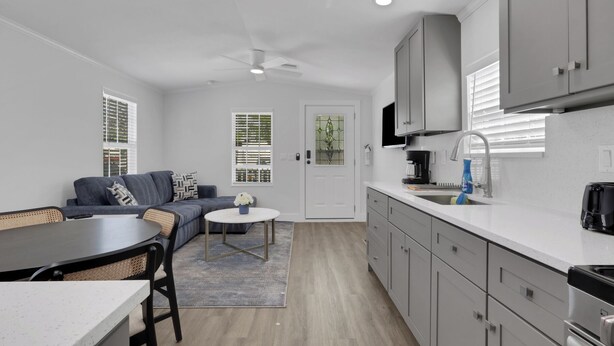 A compact living space with a kitchenette, a dining area with a table and chairs, a sofa, and a small rug. - Renovated Naples Retreat- Resort Pool & Game Room (Naples)