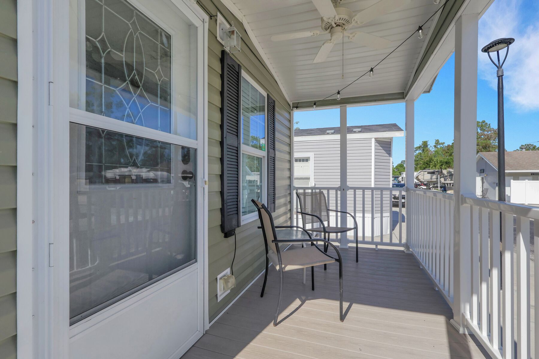 A covered porch with a ceiling fan, a string of lights, and a view of a neighboring house.
