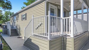 A single-story house with a front porch, a set of stairs leading to the entrance, and a small deck area. - Renovated Naples Retreat- Resort Pool & Game Room (Naples)