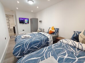 Ein modernes Hotelzimmer mit einem großen Bett, einem an der Wand montierten Fernseher und einem begehbaren Kleiderschrank.