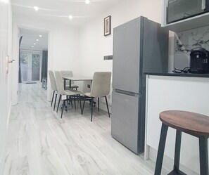 Eine moderne Küche mit Kühlschrank, eine Essecke mit Stühlen und Holzboden.