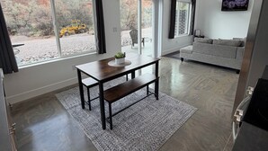 Un intérieur moderne comprenant un coin repas, un canapé, un téléviseur et de grandes fenêtres.