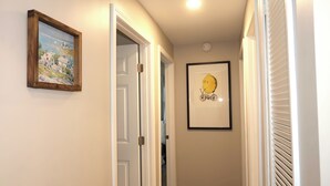 Un corridoio con un quadro incorniciato, una porta e un'immagine appesa al muro.