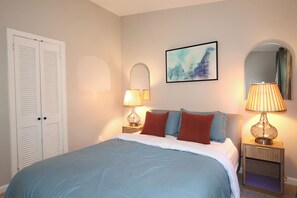 A bedroom with a bed, two bedside lamps, a wall-mounted mirror, and a door. - Charming house in marvelous Marietta perfect for your getaway (Marietta)