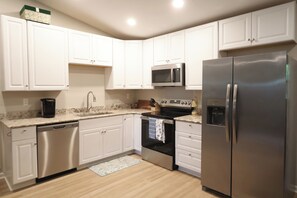 A kitchen with white cabinets, stainless steel appliances, a dishwasher, and a microwave. - Charming house in marvelous Marietta perfect for your getaway (Marietta)