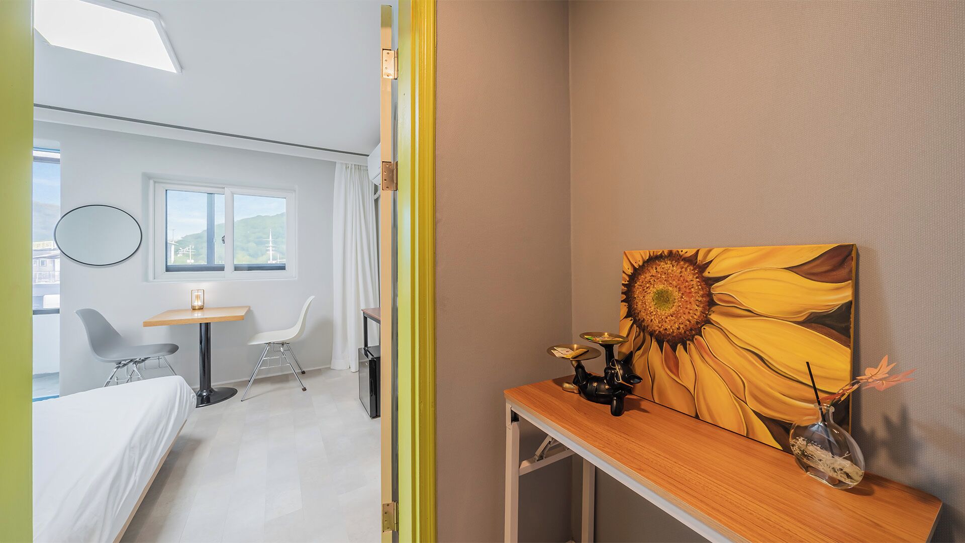 Ein Hotelzimmer mit Bett, Schreibtisch, Stuhl, Fenster mit Blick und einem Bild an der Wand.