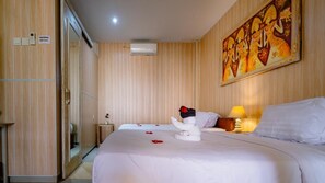 A hotel room with a bed, a nightstand, an air conditioning unit, and a painting on the wall. - Pondok Kedongdong Homestay (Kutuh)
