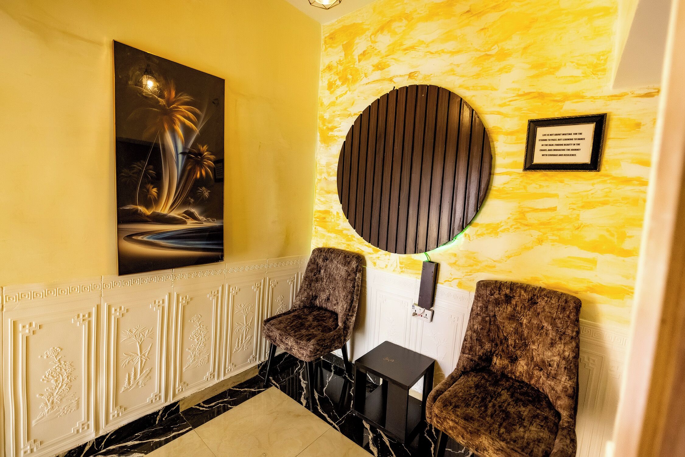 Un espace d’accueil comprenant deux chaises, un tableau, un élément décoratif circulaire fixé au mur et une plaque commémorative.