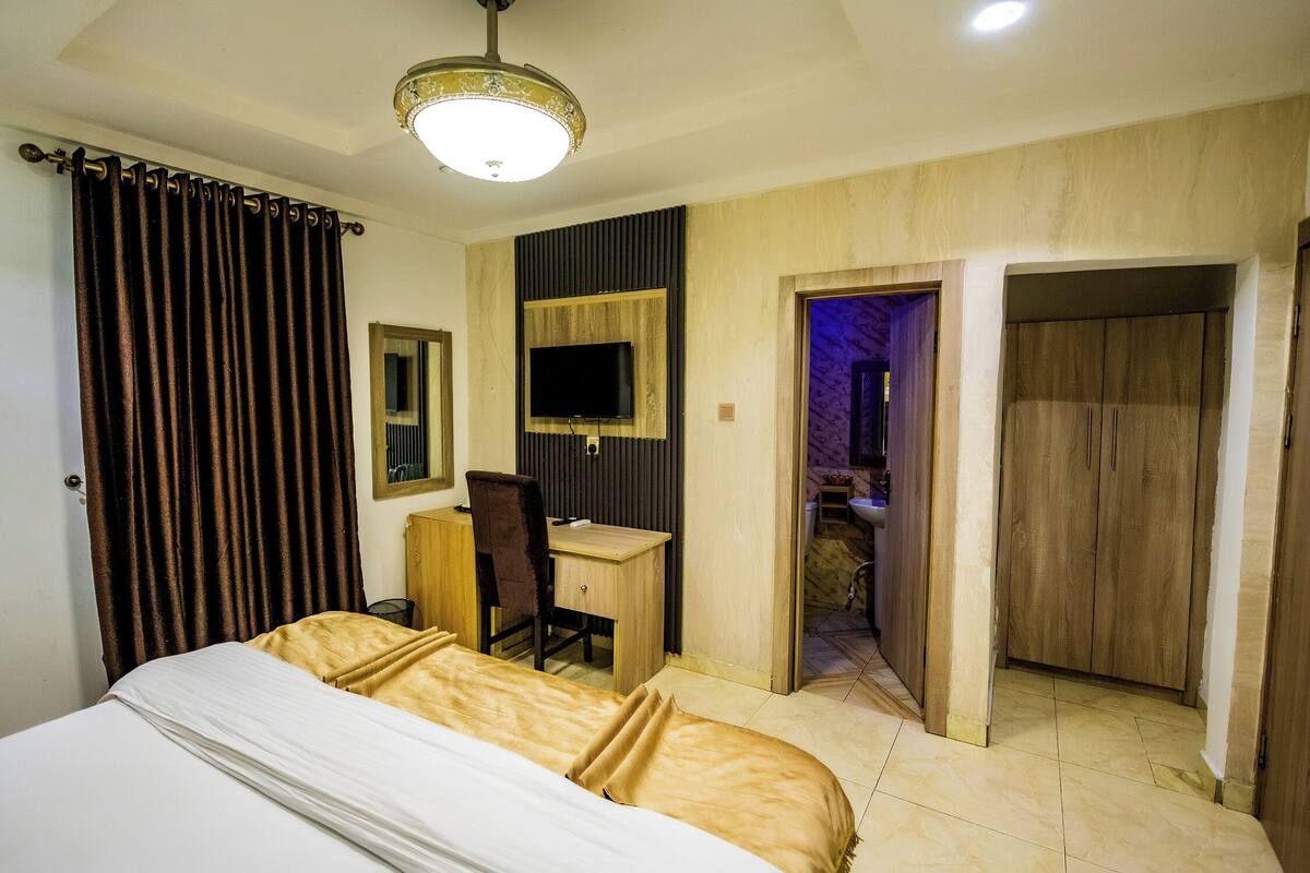 Una camera d'albergo con letto, scrivania, sedia, televisore e armadio.