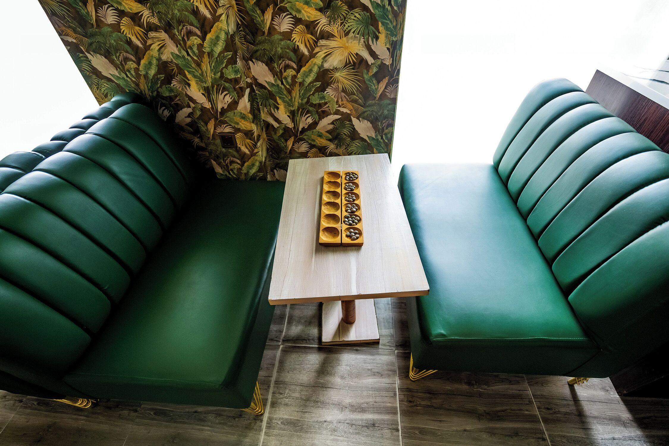 A green sofa set with a wooden table in between, a patterned wall, and a wooden floor.