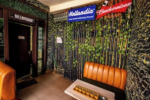 Un bar y restaurante con un cartel que indica prohibido el acceso a no residentes, un letrero de Budweiser y un letrero de Hollandia.