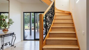 Un escalier en bois avec des rampes en fer noir, une plante en pot et une grande fenêtre.