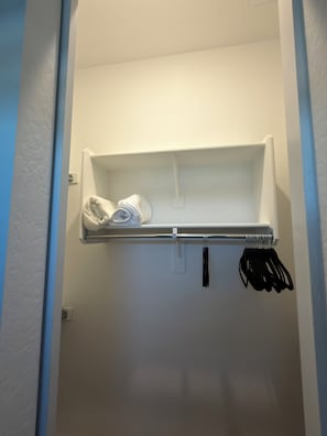 Un pequeño mueble de almacenamiento blanco fijado a la pared, con una barra metálica y ganchos.