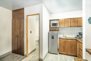 A compact kitchen with wooden cabinets, a stainless steel refrigerator, and a microwave. - Villa Favare - 10 Private Suites in Downtown Jaco (Jaco)
