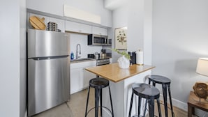 Eine moderne Küche mit Edelstahlgeräten, einem Holztisch und schwarzen Barhocker.