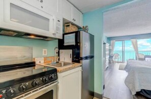 A compact kitchenette with a stove, microwave, and refrigerator. - Dolphin Watcher’s Dream - Myrtle Beach, SC (Myrtle Beach)