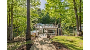 Un chalet au bord du lac, doté d’une terrasse et entouré d’arbres.