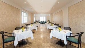 A conference room with multiple tables and chairs, arranged in a U-shape, with a view of a large window in the background. - Hotel Gambara (Gambara)