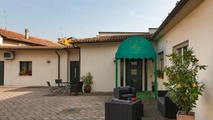 A courtyard with outdoor seating, a green awning, and a potted plant. - Hotel Gambara (Gambara)