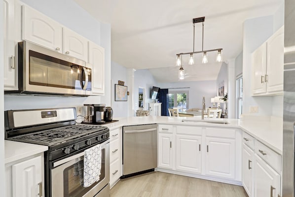 A modern kitchen with white cabinetry, a stainless steel range, a dishwasher, and a coffee maker. - Bluffton Park's own piece of Utopia, a charming single-level, 2-bedroom townhome (Bluffton)