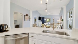 Een moderne keuken met een RVS spoelbak, witte kasten en een hangende lamp.