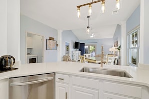 A modern kitchen with a stainless steel sink, white cabinetry, and a hanging light fixture. - Bluffton Park's own piece of Utopia, a charming single-level, 2-bedroom townhome (Bluffton)