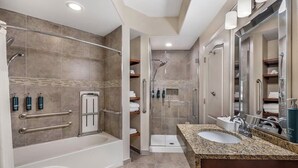 Ein modernes Badezimmer mit Badewanne, Dusche und Waschbecken, ausgestattet mit Haltegriffen und Ablageflächen.