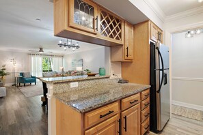 A kitchen with wooden cabinets, a granite countertop, and a stainless steel refrigerator. - Cozy 2-bedroom 2nd floor, end unit condo in charming Sarasota (Sarasota)