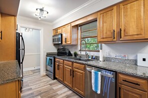 A kitchen with wooden cabinets, granite countertops, stainless steel appliances, and a 'No Clumsy Attitudes' sign. - Cozy 2-bedroom 2nd floor, end unit condo in charming Sarasota (Sarasota)