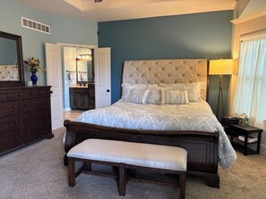 A bedroom with a large bed, a bench, a dresser, a mirror, and a lamp. - Spacious KC World Cup Retreat   4 bath   Sleep 7   Free Parking   Entire Home (Kansas City)