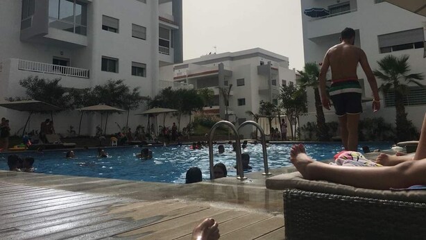 A swimming pool area with multiple levels of buildings, a poolside lounge, and a poolside bar.