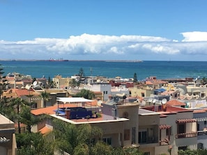 A coastal residential area with buildings, a view of the sea, and a distant ship. - Cosy apartment with pool view and waterfront (Mohammédia)