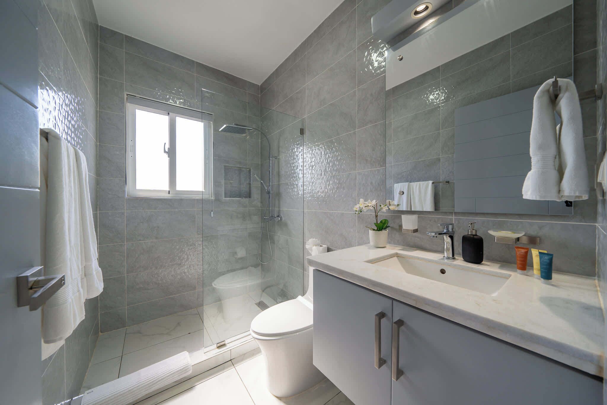 A modern bathroom with a shower, toilet, and vanity.
