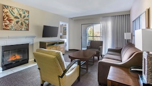 A hotel room with a fireplace, a TV, a sofa, a chair, a table, and a window with curtains. - Luxury Grand Vacation Stay in Mountainous Sedona (Sedona)