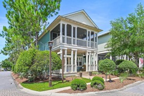 A two-story house with a porch, a covered front porch area, and a small front yard with landscaping. - Beach Blessings | 4BR 30A | Sleeps 8 | 6 Seater Golf Cart + Bikes (Santa Rosa Beach)