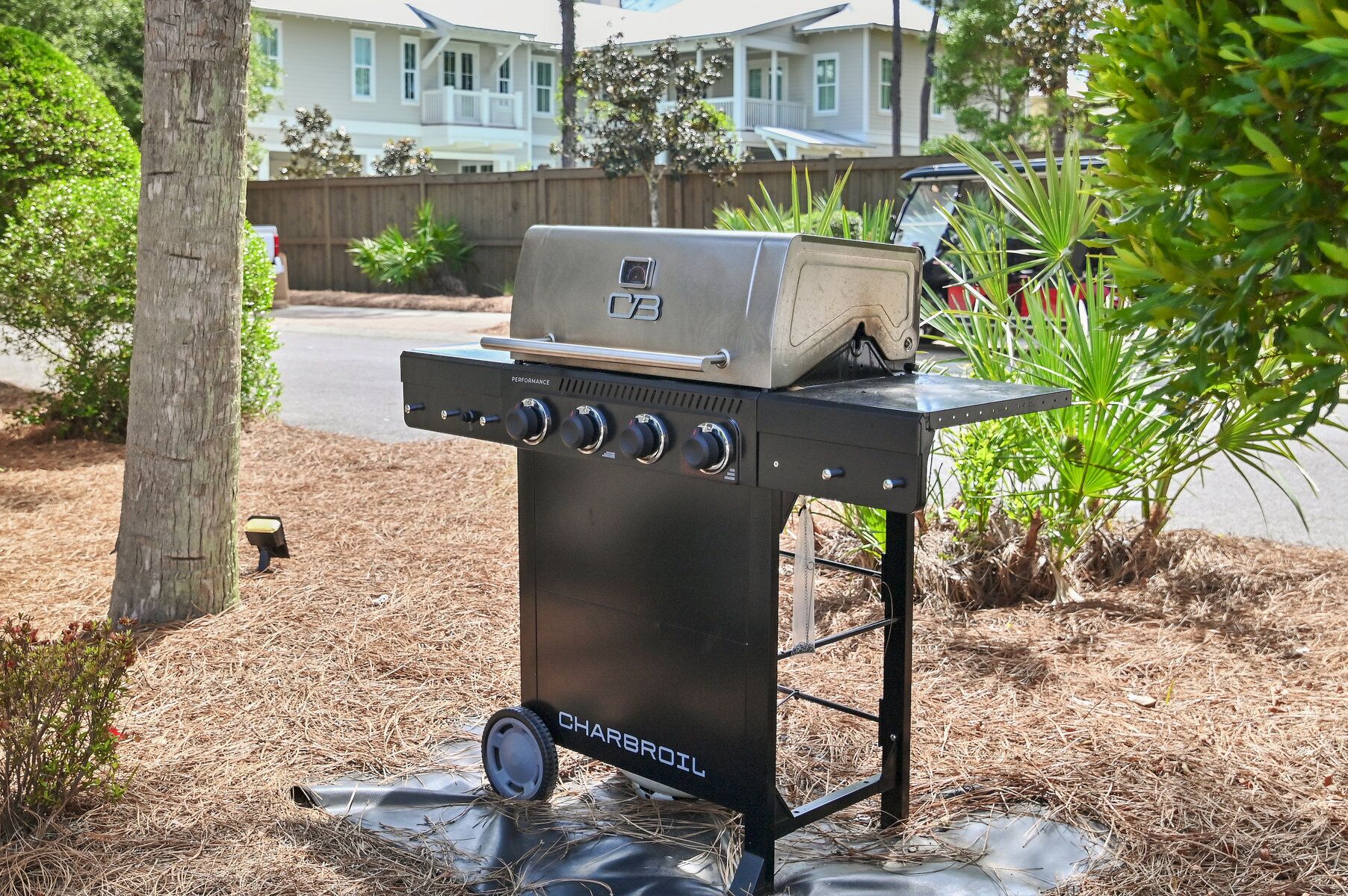A charcoal grill with a performance label, wheels, and a brand name on a stand.