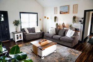 Ein Wohnzimmer mit zwei Sofas, einem Couchtisch, einem Schrank und einem großen Fenster.