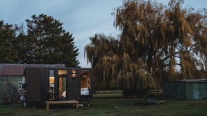 A small wooden cabin with a visible bedroom and a dining area.