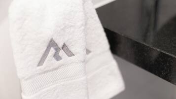 Una toalla blanca con un logotipo gris sobre una encimera de baño.
