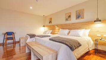 A bedroom with a wooden headboard, a bed with white linens, a bench, a chair, and a bedside table with a phone.
