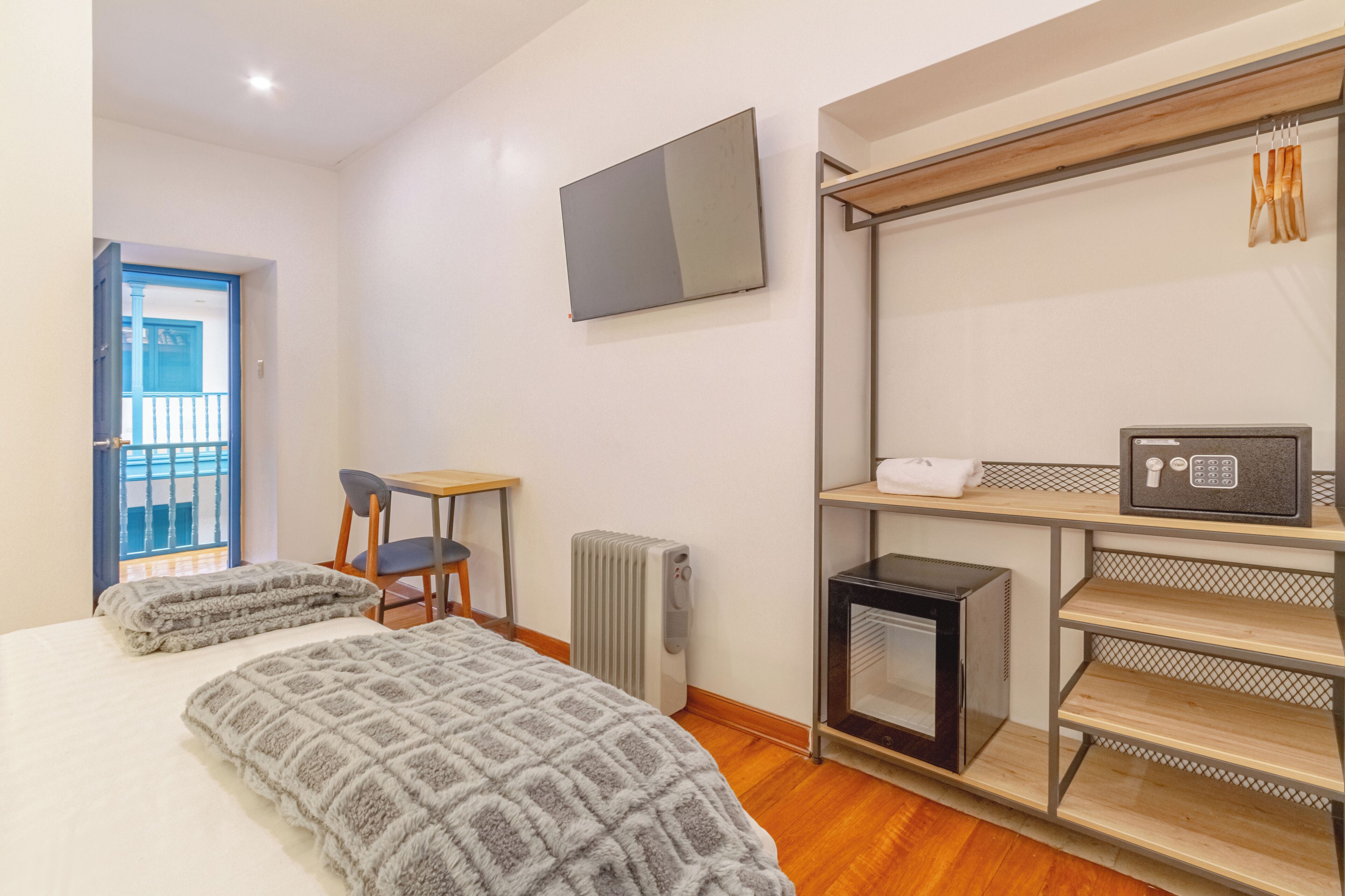 Un dormitorio con cama, escritorio, silla, radiador, televisor y microondas.