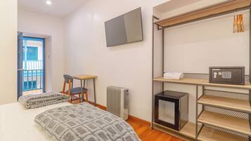 Un dormitorio con cama, escritorio, silla, radiador, televisor y microondas.