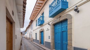 Una estrecha calle adoquinada flanqueada por edificios con puertas y balcones azules.