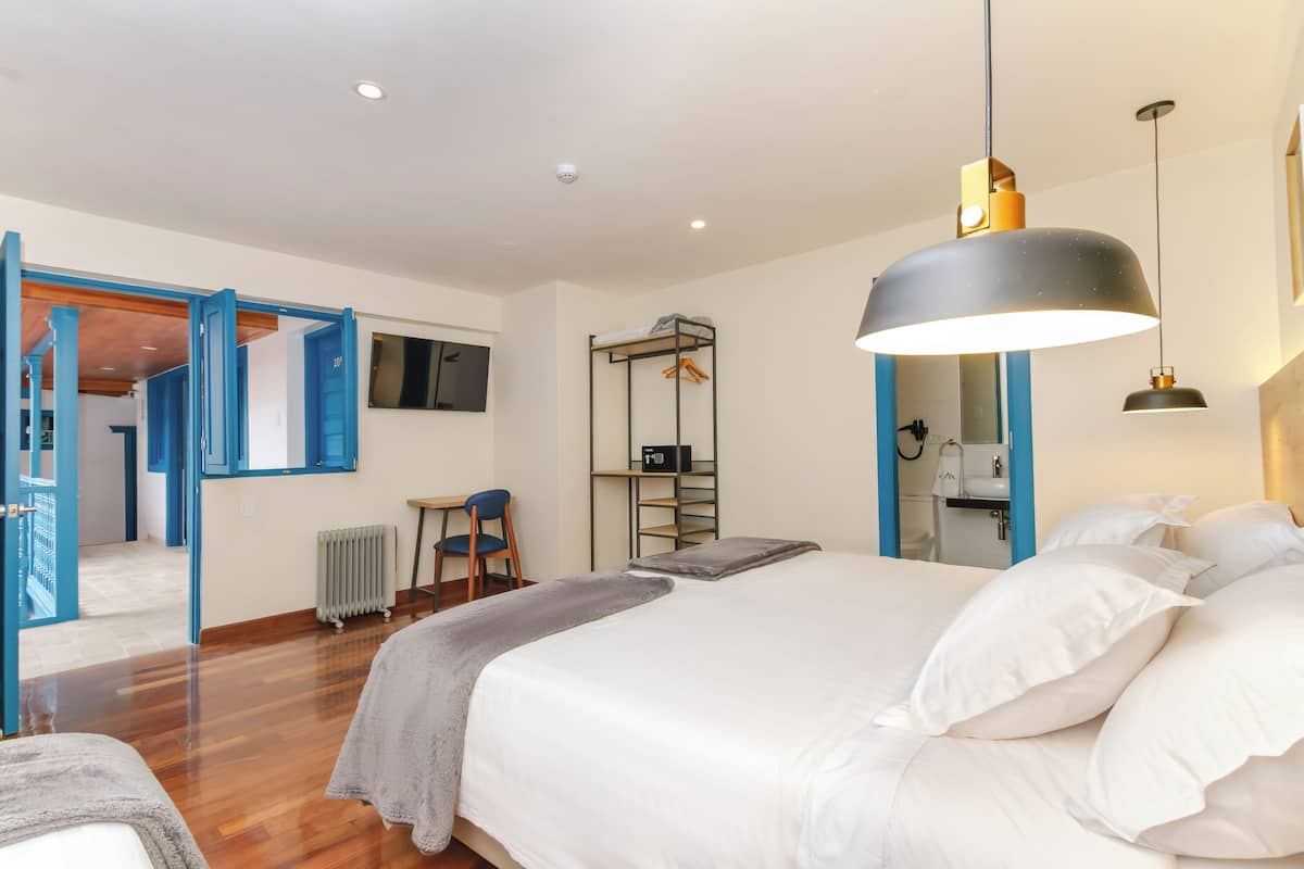 Quarto com cama, luminária pendente, radiador e espelho com moldura azul.