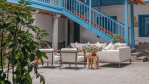 Una escalera con barandillas azules, un sofá blanco y una mesita con una planta.