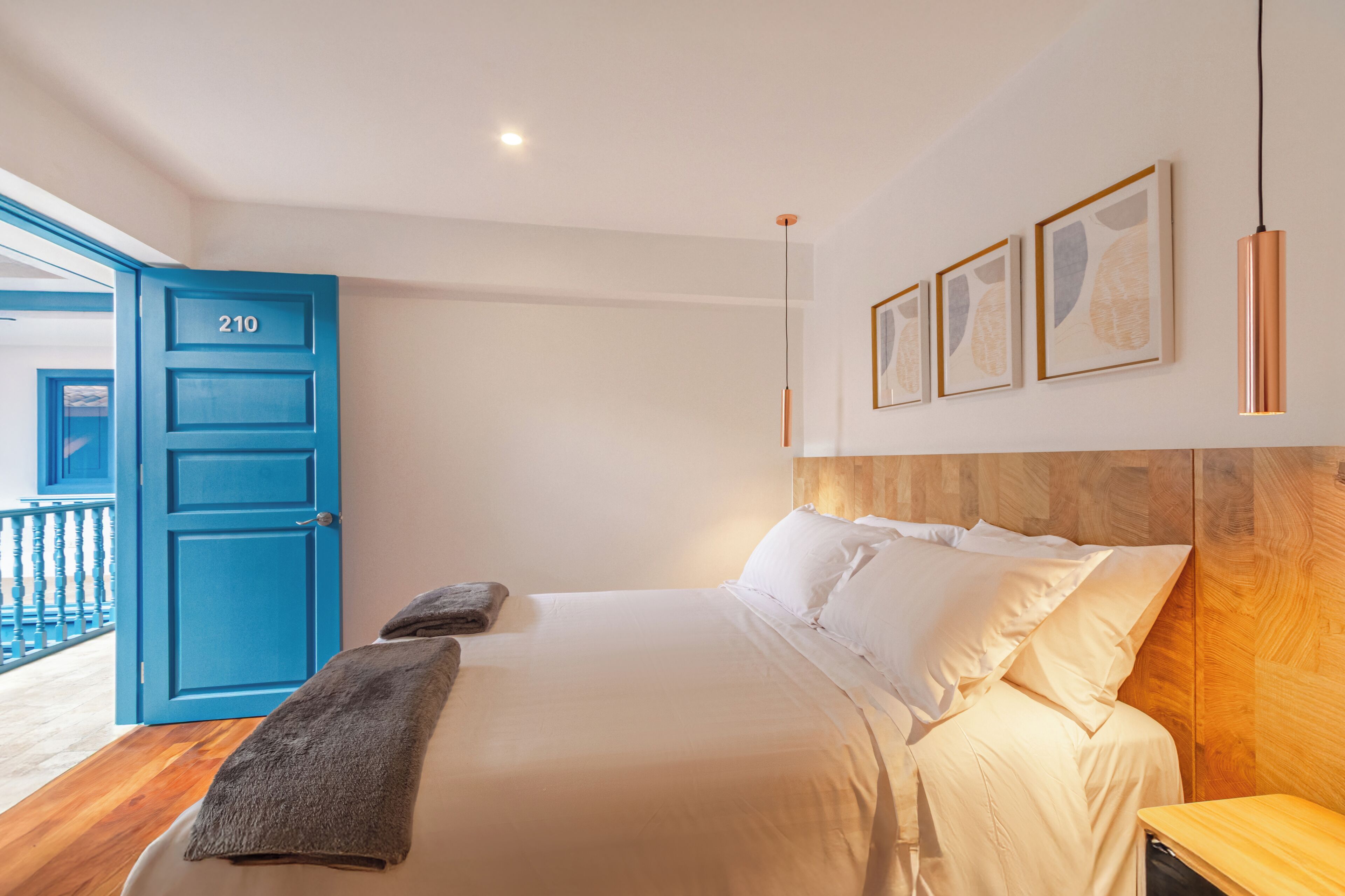 A bedroom with a large bed, a blue door, and a wooden headboard.