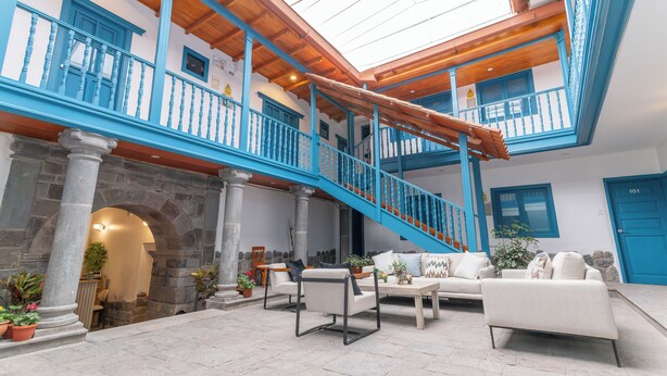 Un amplio patio con una escalera de madera, columnas de piedra y mobiliario para exteriores.